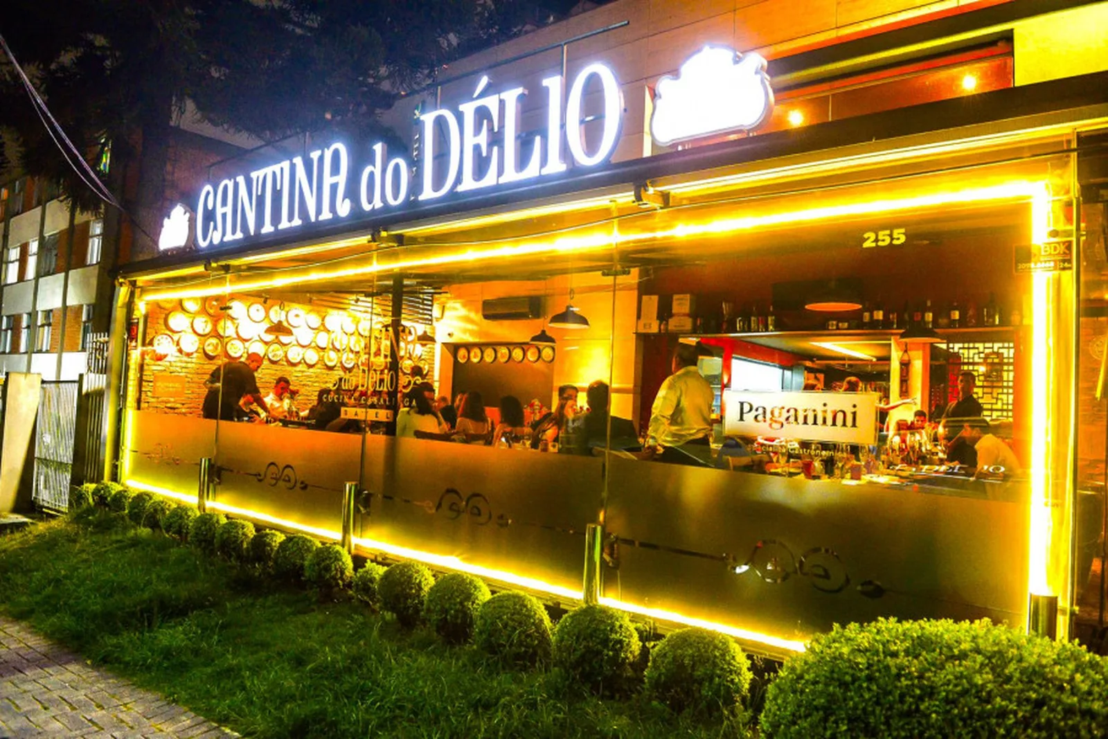 Fachada da Cantina do Délio no Batel, à noite, com o letreiro aceso